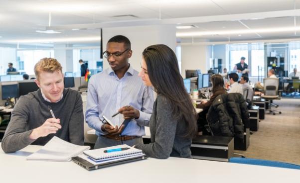 Ares Management employees collaborating at a desk Ares Management employees collaborating at a desk